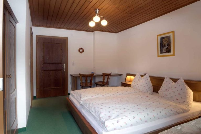 Gemütliches Doppelzimmer in der Pension Forsthof Maishofen mit Holzdecke und Schreibtisch