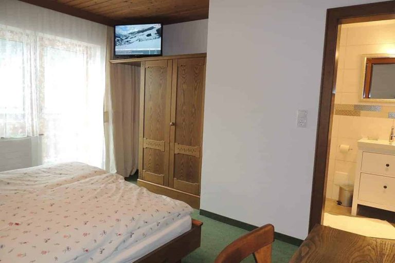 Gemütliches Doppelzimmer mit Holzmöbeln, Bad und Balkon in der Pension Forsthof Maishofen